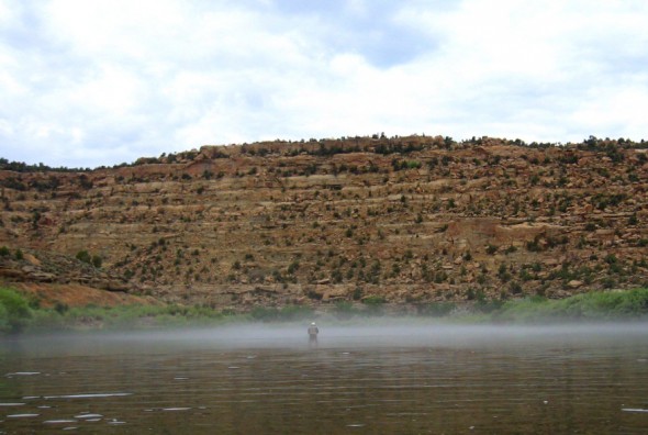 man standing in fog on river